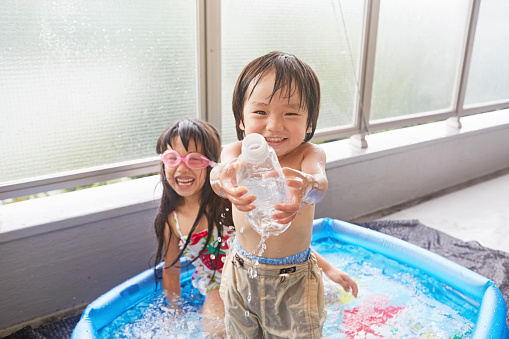 Two children of Japan playing in a plastic pool in the house of veranda