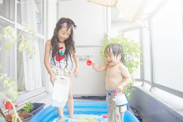 Two children of Japan playing in a plastic pool in the house of veranda