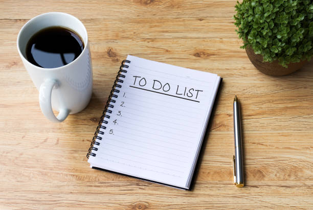 コーヒー、オフィスの机の上にペンとメモ帳にリストを行うに - やることリスト ストックフォトと画像