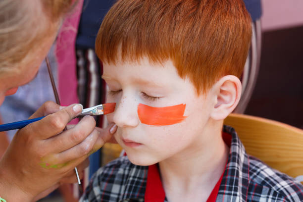 istock Child boy face painting, making tiger eyes process 863655892