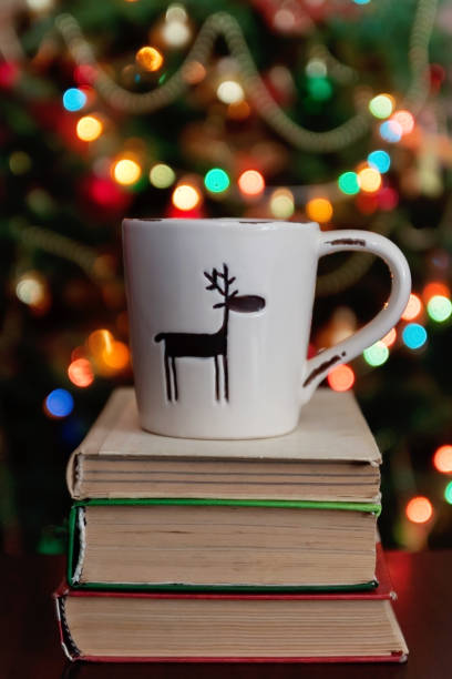 istock Christmas celebration with cup and gift box on books over bokeh and trees background 863661510