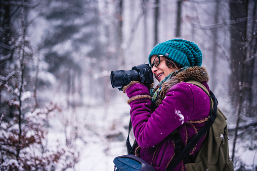 Phot of a woman using professional photo gear in wilderness in a winter time.