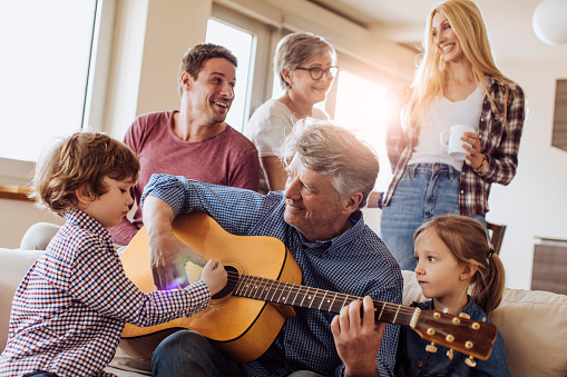 Whole family spending time together while grandpa's playing guitar