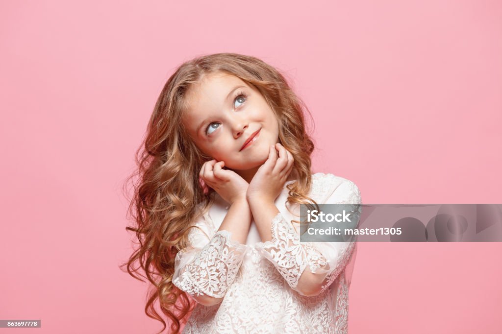 The beautiful little girl in dress standing and posing over white background The beautiful little girl in long dress standing and posing over pink background Girls Stock Photo