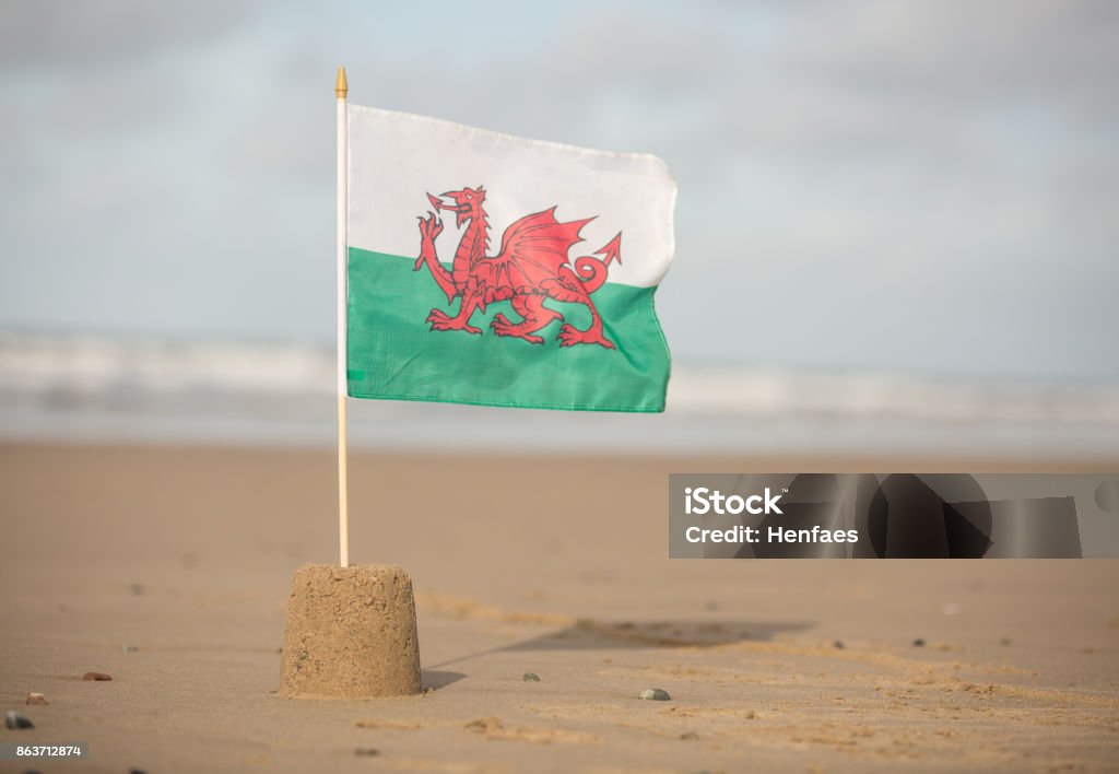 Welsh Flag flying in a sandcastle on a beautiful Cymru beach Beach Stock Photo