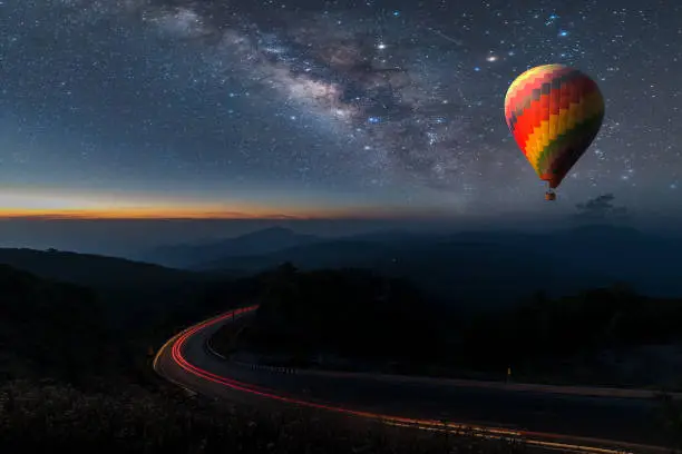 Hot air balloon flying over Chiang Mai Viewpoint Thailand under the sky with milky way and shininng star at night (with grain)