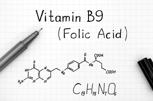 Chemical formula of Vitamin B9 (Folic Acid) with black pen. Close-up.