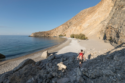 A female hiker is approaching in the early morning the hidden beach of Glika Nera at the southwestern coast of Crete.
