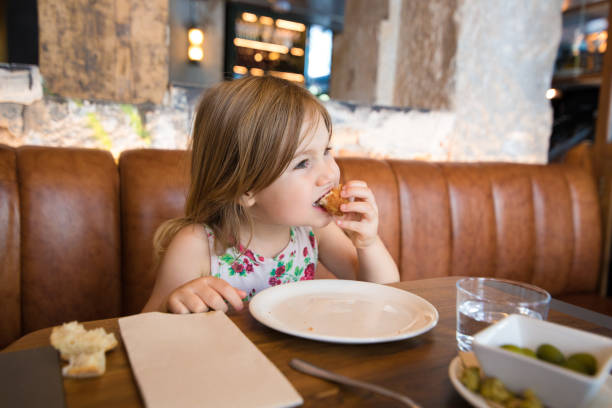 레스토랑에서 손으로 크로켓을 먹는 어린 소녀 스톡 사진