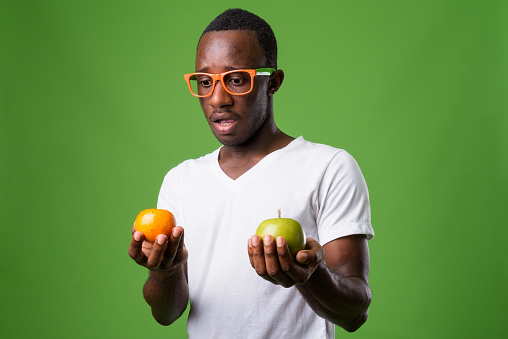 Studio shot of young African man wearing white shirt against green background horizontal shot