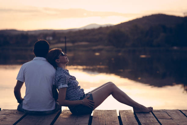 istock Couple enjoying sunset at lake pier 863746396