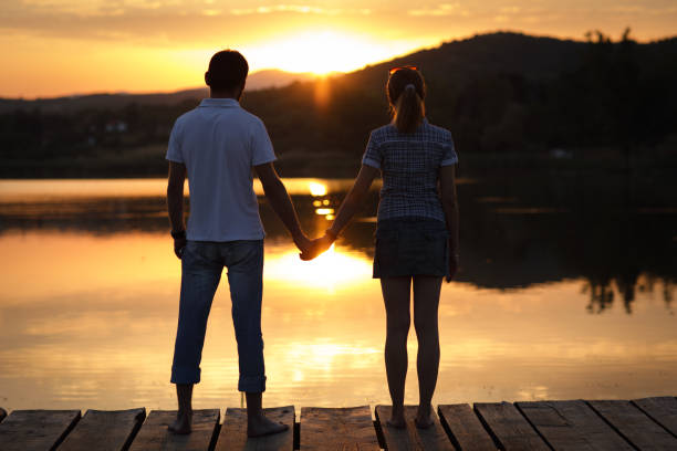 istock Couple enjoying sunset at lake pier 863747312