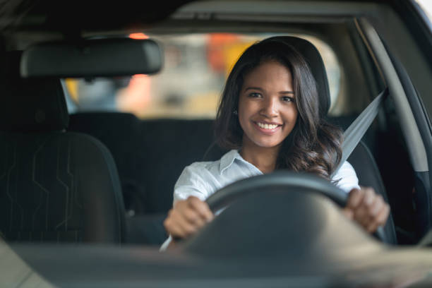 donna felice alla guida di un'auto in concessionaria o in garage - woman driver foto e immagini stock