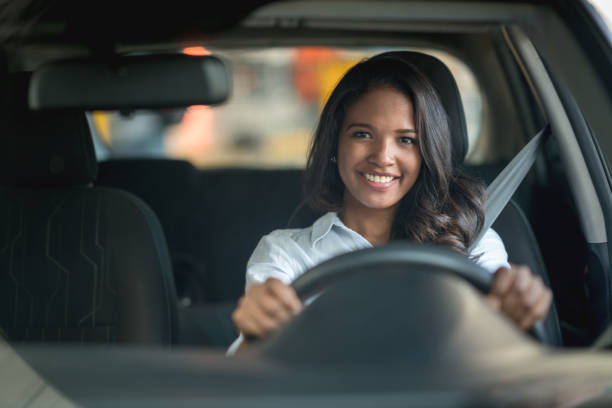 happy woman driving a car at the dealership or the garage - car test drive car rental women imagens e fotografias de stock