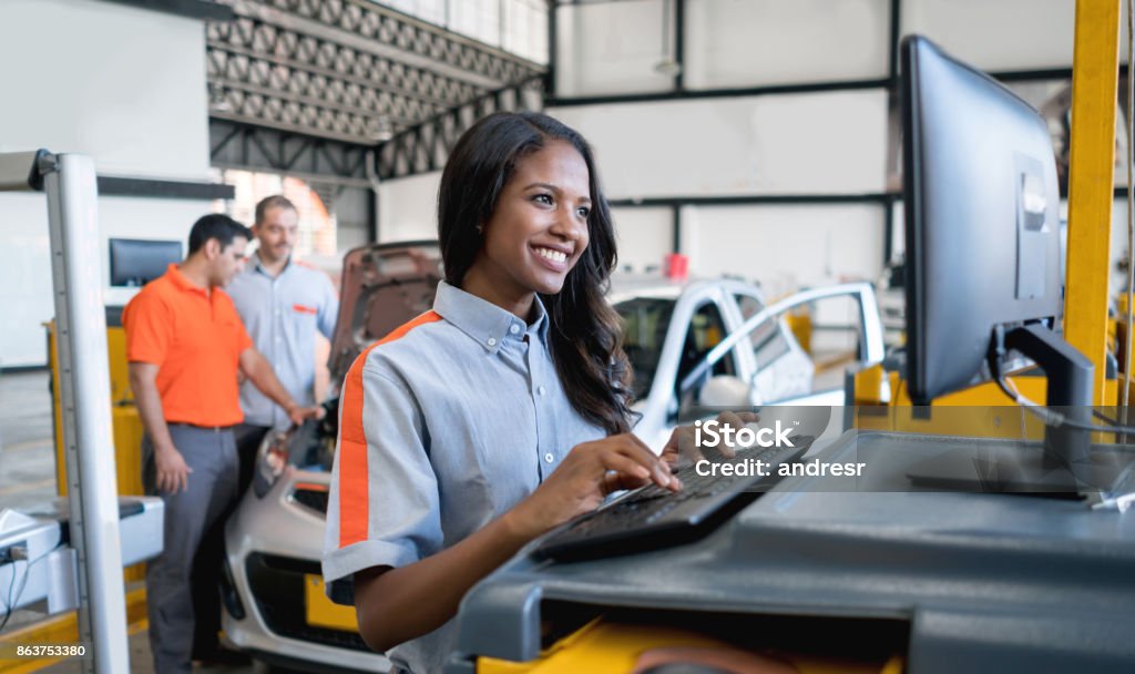 Woman working at an auto repair shop Portrait of a happy woman working at an auto repair shop using the computer Auto Repair Shop Stock Photo