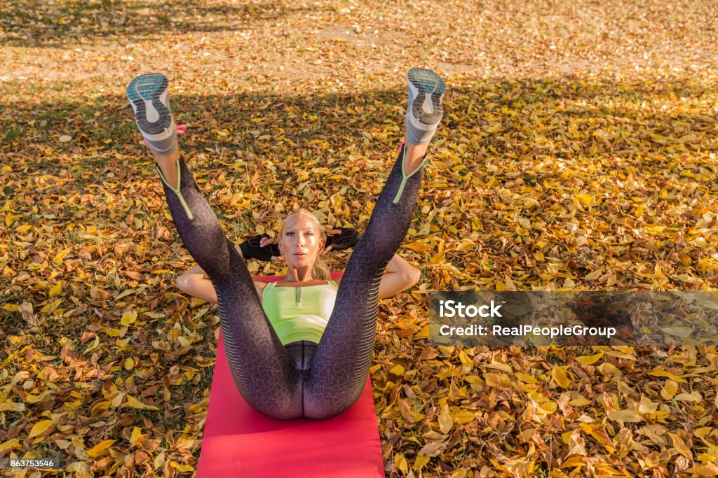 Fitness woman training outside in autumn park. Sport woman doing exercises during workout Beautiful woman working out in autumn park.Young fit woman preparing for autumn training in park. Autumn Stock Photo