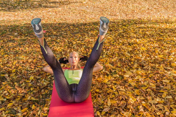 fitness kobieta trenuje poza jesiennym parkiem. sport kobieta robi ćwiczenia podczas treningu - plain shirt zdjęcia i obrazy z banku zdjęć