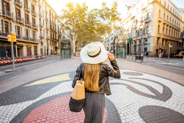 Young woman tourist walking back on the central street with famous colorful tiles in Barcelona city