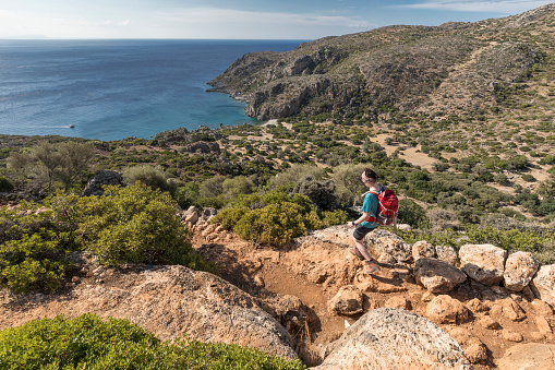A female hiker is walking down into scenic Agios Kirikos Bay nearby the village of Sougia at the southwest coast of Crete. The ancient site of Lissos is situated in that Bay.
