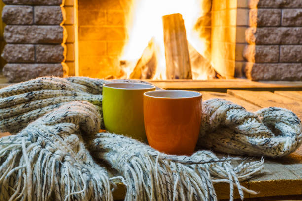 Mugs  for tea or coffee,  wool things near cozy fireplace.