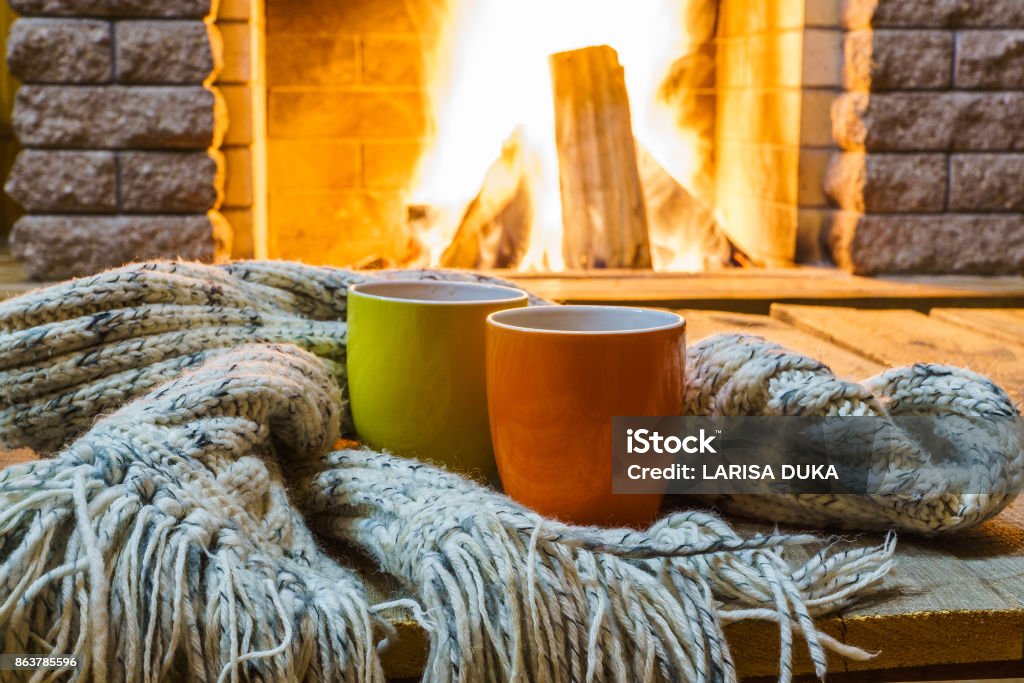 Mugs  for tea or coffee,  wool things near cozy fireplace. Mugs  for tea or coffee,  wool things near cozy fireplace, in country house, winter vacation, horizontal. Winter Stock Photo