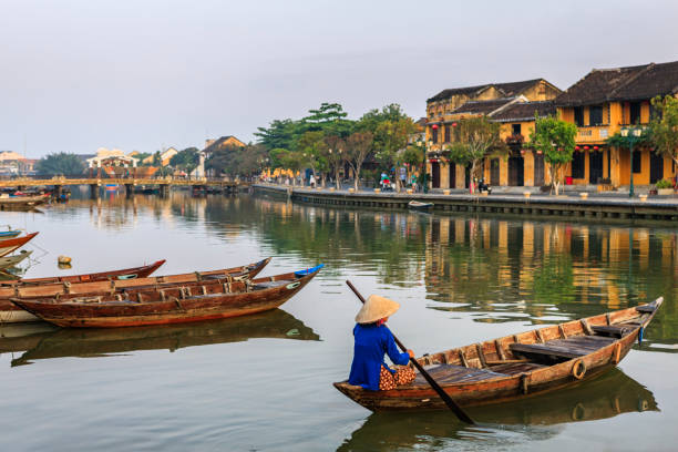 donna vietnamita che pagaia nel centro storico della città di hoi an, vietnam - japanese lantern immagine foto e immagini stock