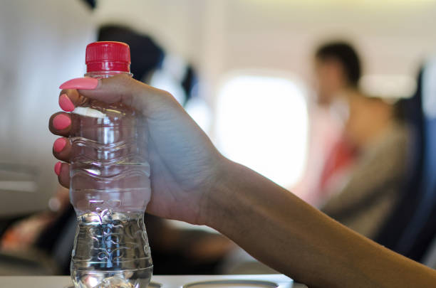 istock Passenger holding bottle of water in airplane 863839452