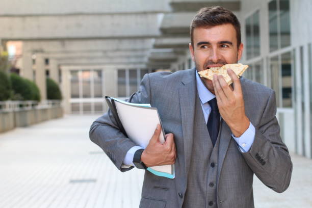 businessman eating a sandwich on the go - eating sandwich emotional stress food imagens e fotografias de stock