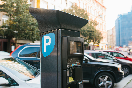 Close-up - machine for paying parking on background of blurry cars