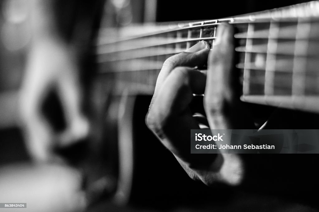 Playing Guitar Guy playing acoustic guitar. Black and white colors and hand focused. Acoustic Guitar Stock Photo