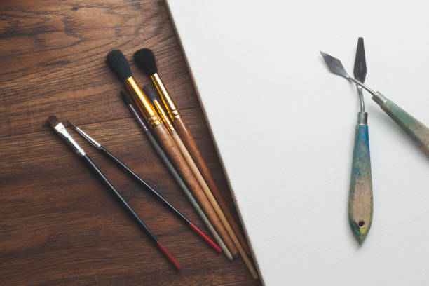 istock paint brushes and blank canvas over wooden background 863857610