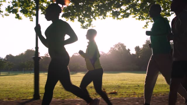 Group of friends running outdoors in the park in London. They are focused and determined.