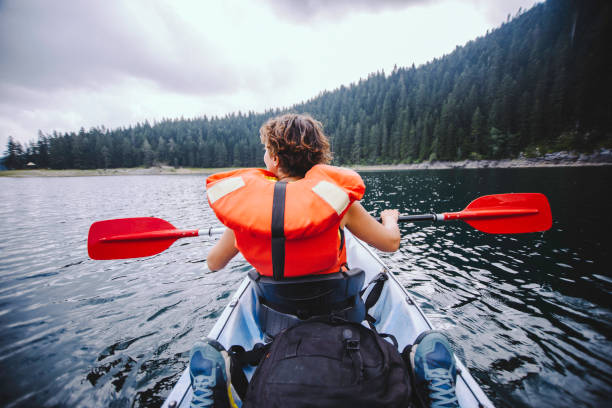 Photo of a woman canoeing in the lake, shooted from the back.