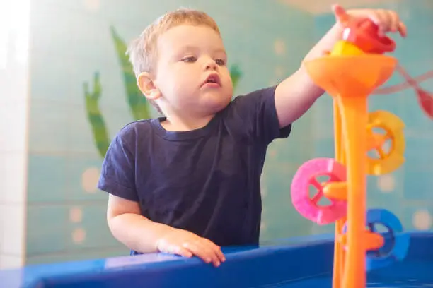 Toddler interacting with toys and educational equipment at nursery or children’s museum