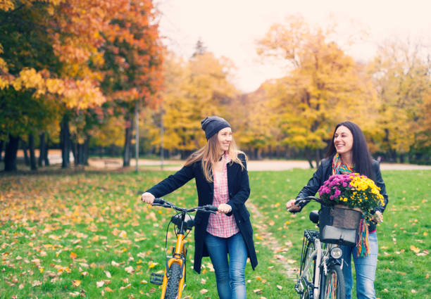 istock Two women pushing bikes in park and talking 863910284