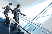 Two Blindfolded Business People Navigate Staircase