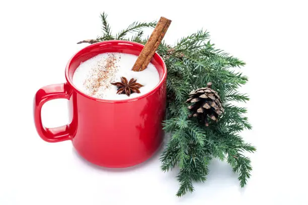 eggnog cocktail in red mug arranged with christmas decoration isolated on white background