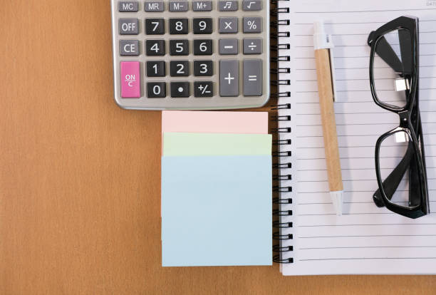 istock sticky note, calculator, ballpoint pen, empty notebook, eyeglasses on office desk. business, accountant concept. Top view with copy space. selective focus. 863948004