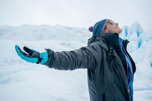 Portrait of a woman with arms open and looking very happy at a glacier