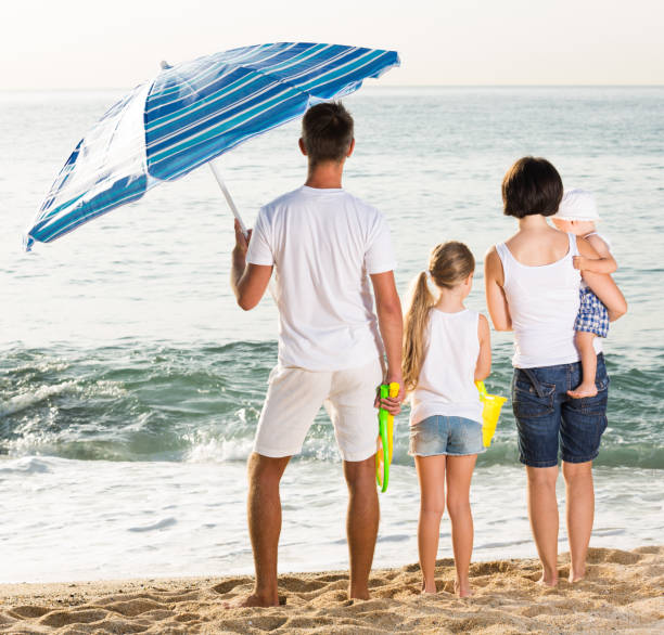 istock back view on family of four standing on beach 863961520