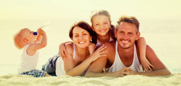 istock couple with two children lying on beach 863963448