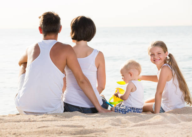istock back view on family of four sitting on beach 863963582