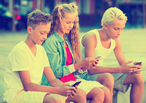 istock Three children keened on mobile phones during joint walk around city 863963778