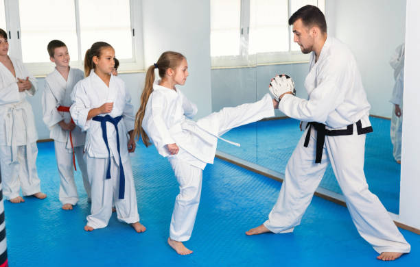 istock Children training karate kicks on punching bag during karate class 863963794