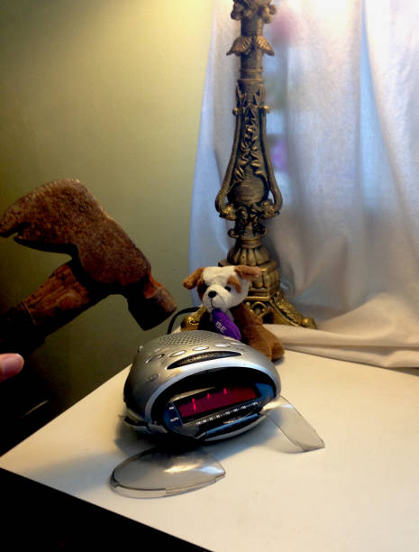 A fed up person smashes an alarm clock A stuffed dog looks on as a clock is shattered with a hammer. smash alarm clock stock pictures, royalty-free photos & images