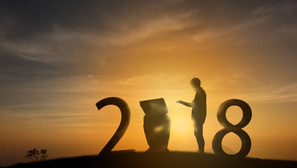 istock futuristic concept, Silhouette friendship man put a hand on to command the robot (artificial intelligence) on the top of the mountain with sunset background and celebrating 2018 new years 863972682
