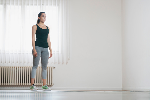 Portrait of a young woman athlete standing in an exercise room, ready for the daily training.