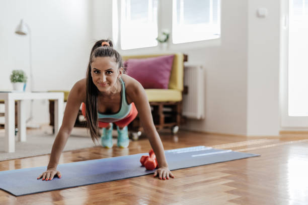 istock Young woman doing some push ups in her living room 863990984