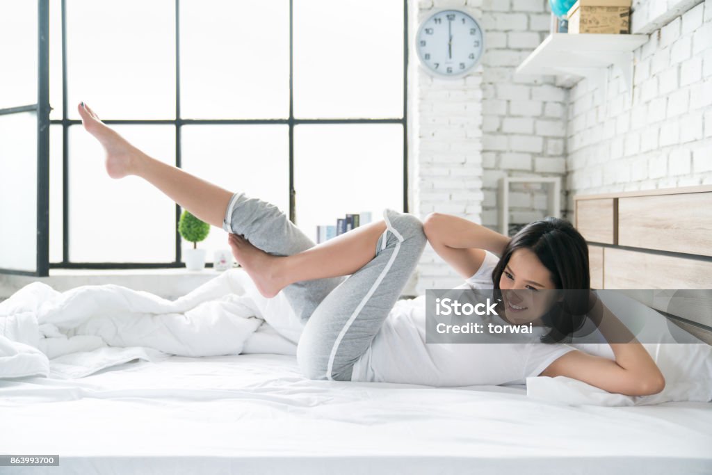 Asian women exercising in bed in the morning, she feels refreshed. Exercising Stock Photo