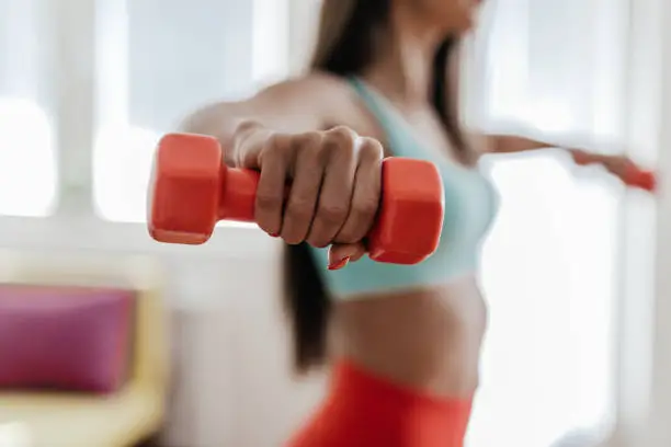 Photo of Young woman exercising with her weights in the living room